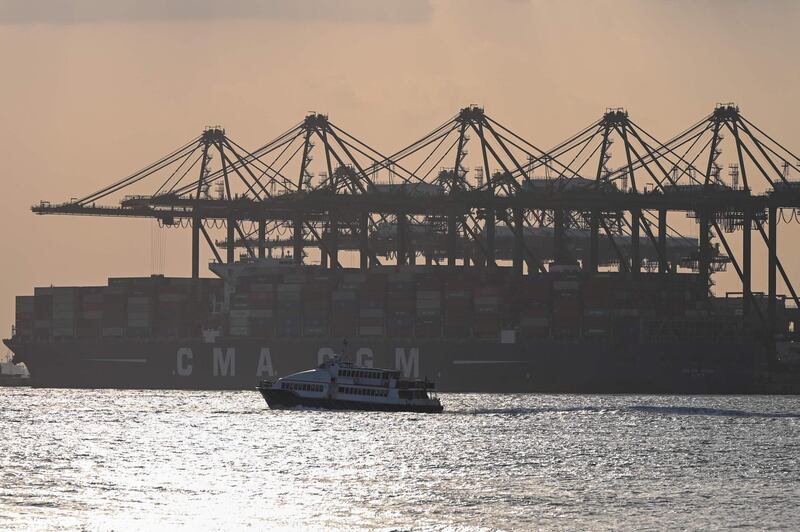 A boat sails past a vessel docked at Pasir Panjang container port at sunset in Singapore on January 18, 2021. / AFP / Roslan Rahman
