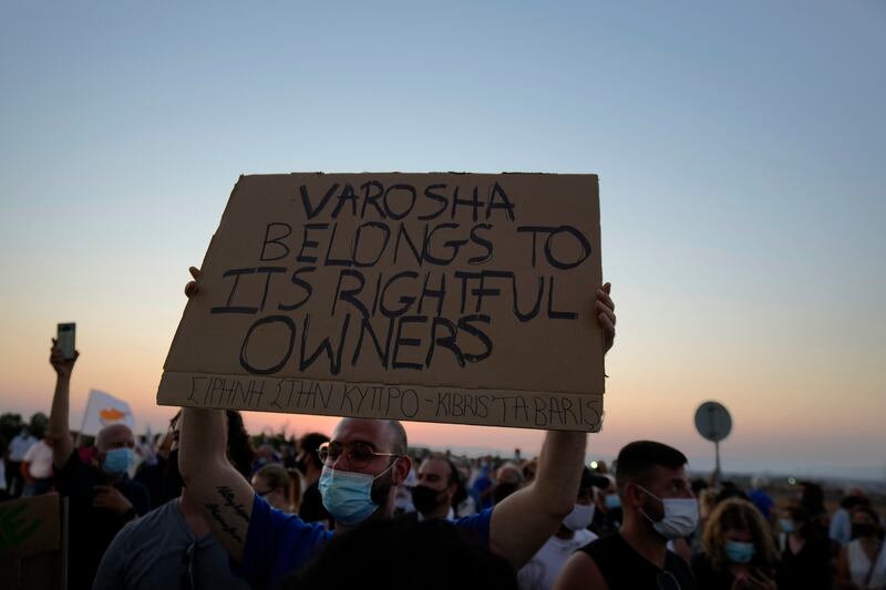 A resident of Varosha, the abandoned city, holds a banner during a protest against the Turkish President visit this week.