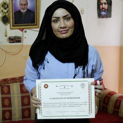 Iraqi female wrestler Alia Hussein poses with her certificate of appreciation awarded by the Lebanese Wrestling Federation, after winning the silver medal during the world championships held in Lebanon, in Diwaniyahh, around 160 kilometres (100 miles) south of the capital Baghdad, on October 6, 2018. Taking on a sport largely reserved for men, Iraq's first women's wrestling squad grapples in the ring but it also wrangles with strict traditions in the country's tribal south. / AFP / SABAH ARAR
