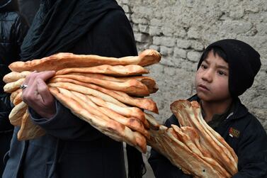 A child holds free bread bread distributed as part of the Save Afghans From Hunger campaign in front of a bakery in Kabul on January 18, 2022.  (Photo by Wakil KOHSAR  /  AFP)