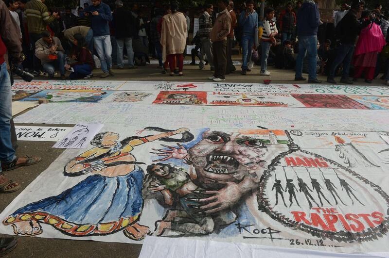 Bystanders look at a banner featuring images of 'government and rapists' in New Delhi after a cremation ceremony for a gang rape victim on December 30, 2012. Several filmmakers are now tackling the subject. Raveendran / AFP





