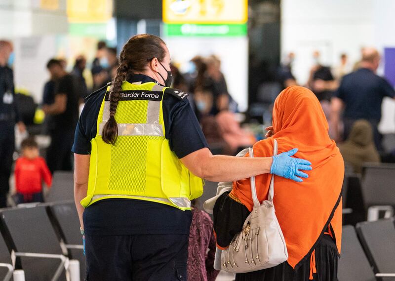 A member of Border Force staff assists an Afghan refugee on her arrival on an evacuation flight from Afghanistan, at Heathrow Airport in London. AFP