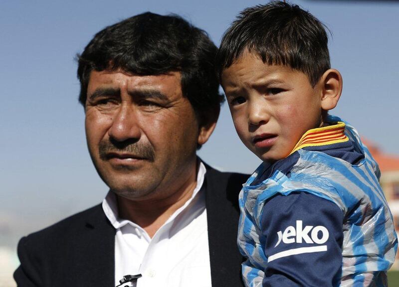 Five year-old Murtaza Ahmadi wears a shirt of Barcelona's star Lionel Messi as his father talks to the media at the Afghan Football Federation headquarters in Kabul, Afghanistan February 2, 2016. Barcelona star Lionel Messi will meet an Afghan boy who gained Internet fame after a touching series of photographs went viral, showing him playing in a shirt improvised from a plastic bag and bearing the name and playing number of his hero. REUTERS/Omar Sobhani