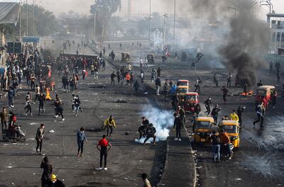 This picture taken on January 20, 2020 shows a view of clashes between Iraqi security forces (background) and anti-government protesters (foreground) as tuktuks (motorised rickshaws) are present on the scene to transport the injured, at Tayaran Square, east of Tahrir Square in the centre of the capital Baghdad.  / AFP / AHMAD AL-RUBAYE
