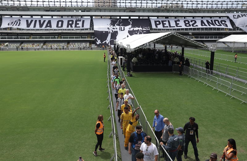 Mourners pay their respects to the late Brazilian legend Pele as he lies in state on the pitch of his former club Santos' stadium. Reuters