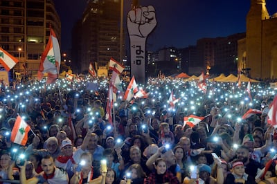 epa08004125 Lebanese protesters light up their phones, shout slogans and carry the national flags next to a fist-shaped banner reading 'Revolution' during a protest call The Peaceful Challenge, in Martyr Square, downtown Beirut, Lebanon, 17 November 2019. Protests continue in Lebanon since first erupted on 17 October, as protesters aim to apply pressure on the country's political leaders over what they view as a lack of progress following the resignation of Prime Minister Saad Hariri on 29 October.  EPA/WAEL HAMZEH