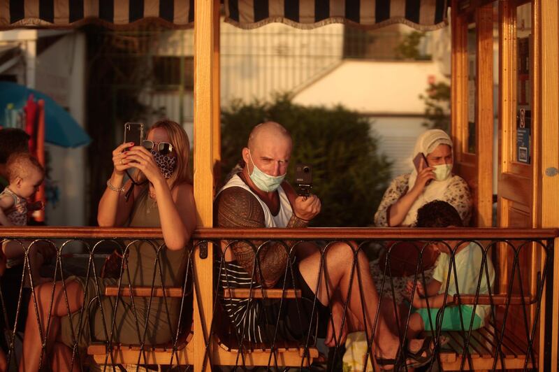 People take photos from a tram in town of Sóller in the Balearic Island of Mallorca, Spain. AP Photo