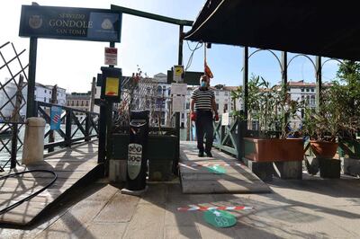 A gondolier wearing a face mask resumes service at the San Toma embankment on a Venice canal on May 18, 2020 during the country's lockdown aimed at curbing the spread of the COVID-19 infection, caused by the novel coronavirus.  Restaurants and churches reopen in Italy on May 18, 2020 as part of a fresh wave of lockdown easing in Europe and the country's latest step in a cautious, gradual return to normality, allowing businesses and churches to reopen after a two-month lockdown. / AFP / ANDREA PATTARO
