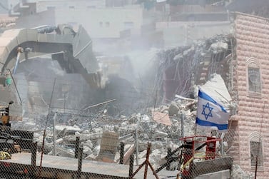 This picture taken from the West Bank on July 22, 2019 shows an Israeli flag waving as Israeli security forces tear down one of the Palestinian buildings still under construction in the Wadi Al Hummus area adjacent to the Palestinian village of Sur Baher in East Jerusalem. AFP