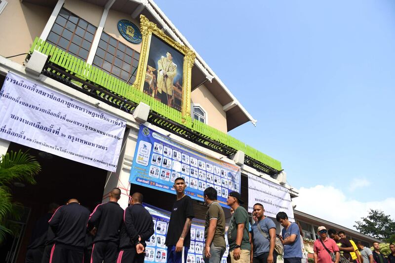 Voters wait in line under a portrait of Thailand's King Maha Vajiralongkorn to cast their ballots at a polling station in Bangkok on March 24, 2019 during Thailand's general election / AFP / Lillian SUWANRUMPHA
