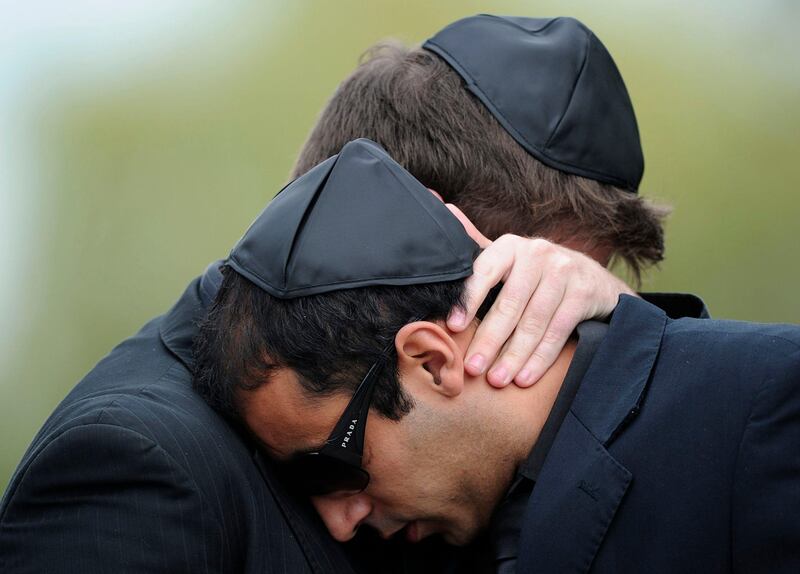 Two mourners comfort each other as they attend a funeral service for the late British singer Amy Winehouse in north London, on July 26, 2011. Amy Winehouse's family, friends and fans paid their last respects to the troubled British soul singer at her funeral on Tuesday, three days after the 27-year-old was found dead at her London home.   AFP PHOTO / CARL COURT
 *** Local Caption ***  497007-01-08.jpg