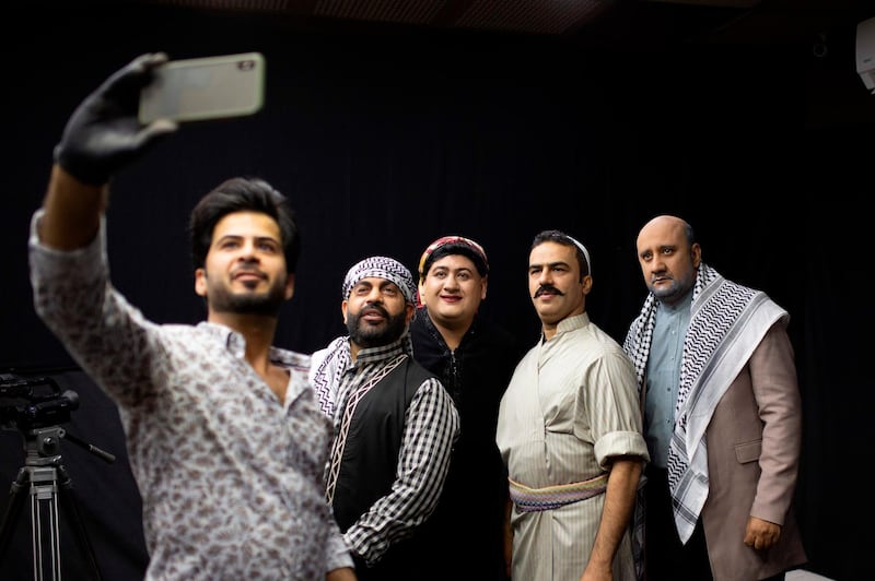The set's makeup artist (L) takes a selfie photograph as he poses with Iraqi actors (L to R) Ayad al-Atabi, Oussama Mahdi, Youssef al-Hajjaj, and Mohammad Qassem on the set of a parody sketch video of Bab al-Hara, an adaptation of an iconic long-running Syrian television drama, in Iraq's southern port city of Basra on April 22, 2020. AFP / Hussein Faleh