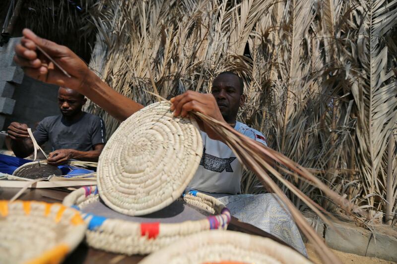 Members of a Palestinian family make traditional decorative objects with palm tree leaves to be sold in the local market, in the central Gaza Strip. Reuters