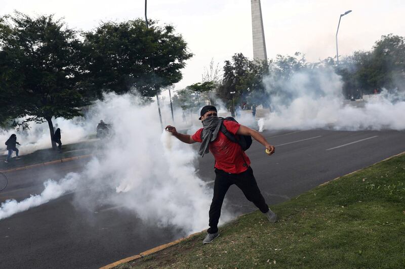 A demonstrator throws a tear gas canister during a protest against the increase in subway ticket prices in Santiago, Chile. Reuters