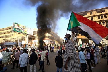 A Sudanese man wearing a face mask waves his country's national flag during protests in the capital Khartoum to mark the second anniversary of the start of a revolt that toppled the previous government, on December 19, 2020. AFP