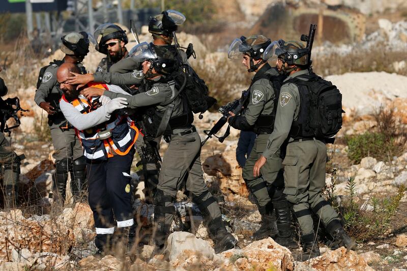 Israeli security forces push back a Palestinian paramedic trying to access a Palestinian demonstrator who was wounded by Israeli security forces during a demonstration against Israeli airstrikes on Gaza, at the Beit El checkpoint near the West Bank city of Ramallah. The injured protester was later taken by paramedics, and not arrested. AP Photo