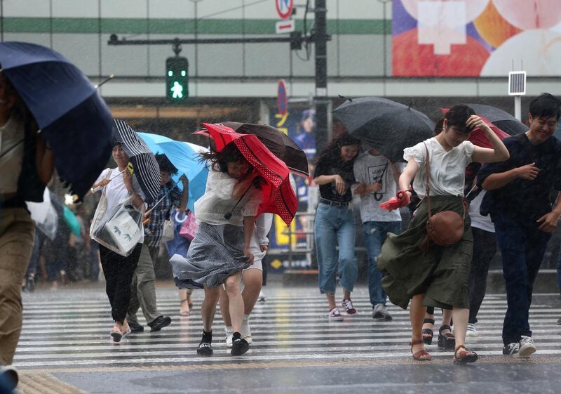 Pedestrians crossing a road struggle against the strong wind and rain in Tokyo, Japan.  EPA / JIJI