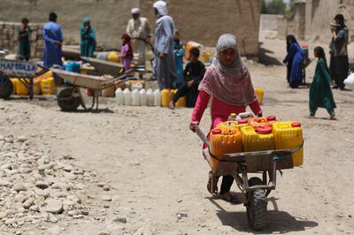 A girl pushes a wheelbarrow loaded with water cans in Jalalabad, Afghanistan. AFP