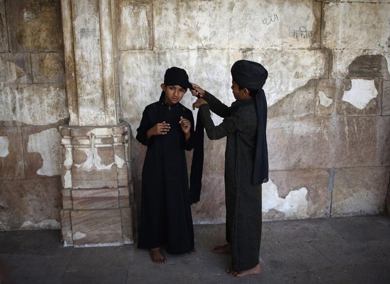 A Muslim boy wraps his friend's turban inside a mosque.