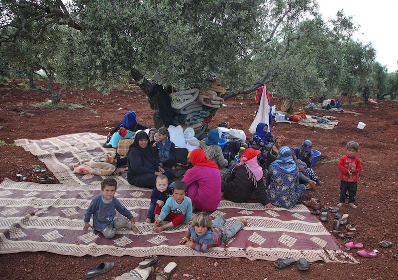 TOPSHOT - Displaced Syrians gather under the shade of a tree in a field near a camp for displaced people in the village of Atme, in the jihadist-held northern Idlib province on May 1, 2019. Bombardment by the regime and its Russian ally on northwestern Syria has displaced nearly 140,000 people since February, the UN said today.  / AFP / Aaref WATAD
