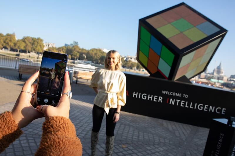 LONDON, ENGLAND - OCTOBER 25: In this handout image provided by Huawei, Georgia Toffolo poses in front of a giant AI-powered Rubiks Cube unveiled by Londons South Bank to celebrate the launch of the new Huawei Mate 20 Pro, the worlds first dual-AI powered smartphone, on October 25, 2018 in London, England. Members of the public are invited to work together with the Artificial Intelligence inside the new Huawei Mate 20 Pro to solve the Cube. (Photo by Tom Nicholson/Huawei via Getty Images)