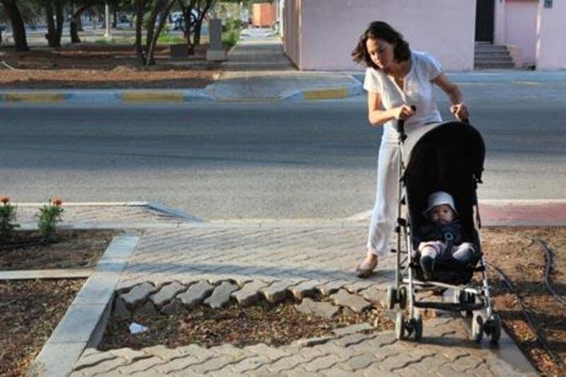 ABU DHABI - 14NOC2010 - Daisy Garder with her 6month old son Thomas Garder in the pram a residence around 13th Street (delma street) finds pavements across her residence are blocked or not maintained to walk safely in Abu Dhabi. Ravindranath K / The National