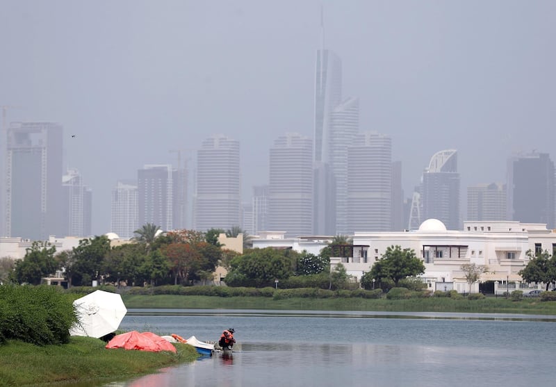 Dubai, United Arab Emirates - July 18, 2019: Weather. Men work to fix a fountain on a hot humid day in Dubai. Thursday the 18th of July 2019. The Springs, Dubai. Chris Whiteoak / The National