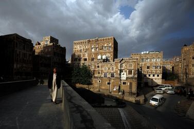 A Yemeni walks through a pedestrian bridge in front of historic buildings in the old city of Sanaa, Yemen. EPA