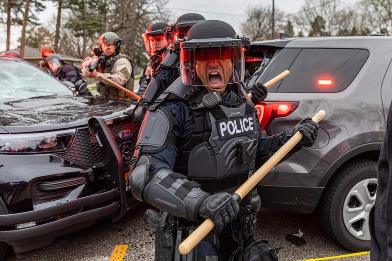 Police officers take cover as they clash with protesters after an officer reportedly shot and killed a black man in Brooklyn Centre, Minneapolis, Minnesota. AFP