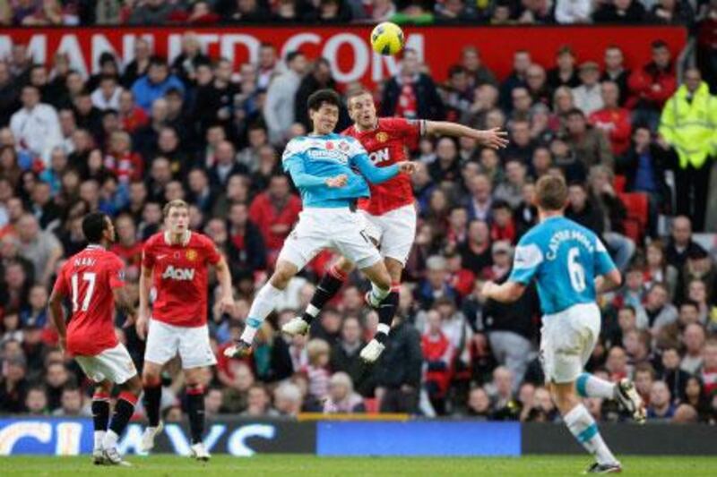 Sunderland's Ji-dong Won, in blue, jumps for the ball with Manchester United's Nemanja Vidic.