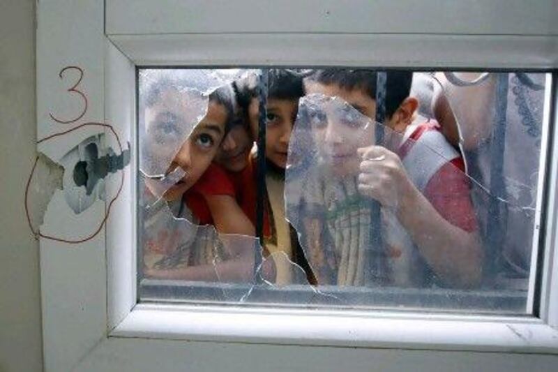 Turkish boys look through a shattered window after an anti-aircraft shell fired from Syria hit a health centre across the border in the Reyhanli district of Turkey's Hatay province.