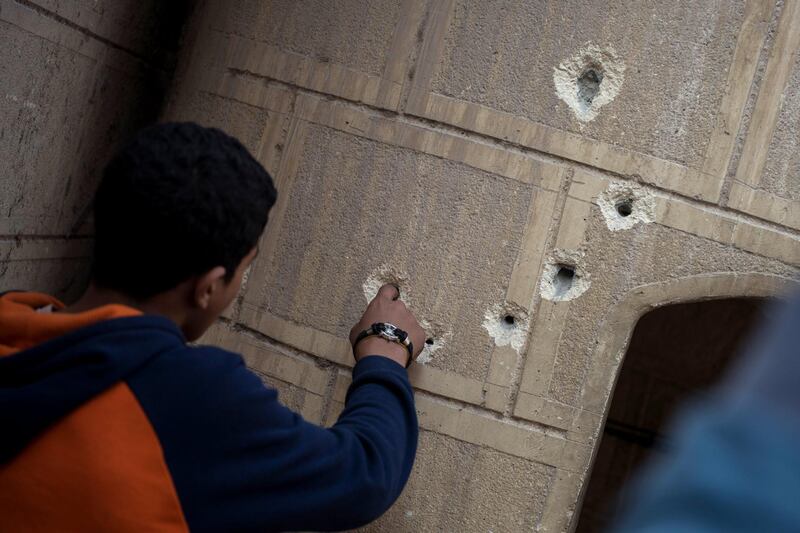 A man points at bullet holes on a construction outside the church.  Mohamed Hossam / EPA