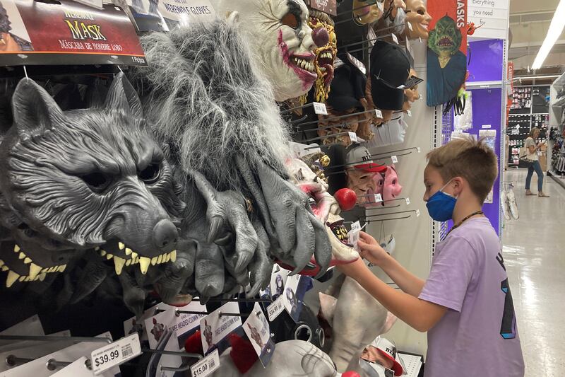 A young customer views Halloween masks. Americans continued to spend at a solid clip in September, despite rising prices and snarled global supply chains limiting the flow of goods. AP