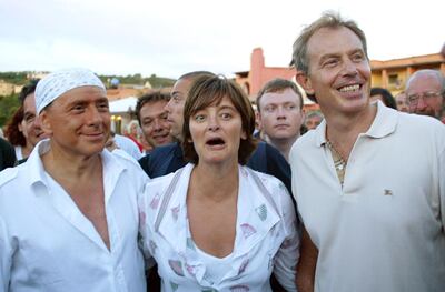Italian Premier Silvio Berlusconi, left,  sporting a print bandanna on his head and a white, loose-fitting shirt with matching white shoes and trousers, goes for a walk British Prime Minister Tony Blair, right,  and his wife Cherie Blair,  after their arrival at Berlusconi's luxury villa, in Porto Rotondo on the Island-region of Sardinia, Italy, Monday Aug. 16, 2004. The Blairs stayed overnight in Berlusconi's Emerald Coast villa. The two leaders engaged in informal talks Tuesday Aug. 17, 2004 on international policy as well as taking a stroll by the sea, Berlusconi's office said. Iraq was central to the discussions. (AP Photo)