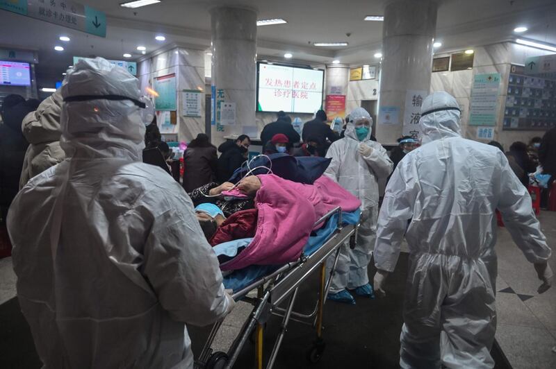 Medical staff wearing protective clothing to protect against a previously unknown coronavirus arrive with a patient at the Wuhan Red Cross Hospital.  AFP