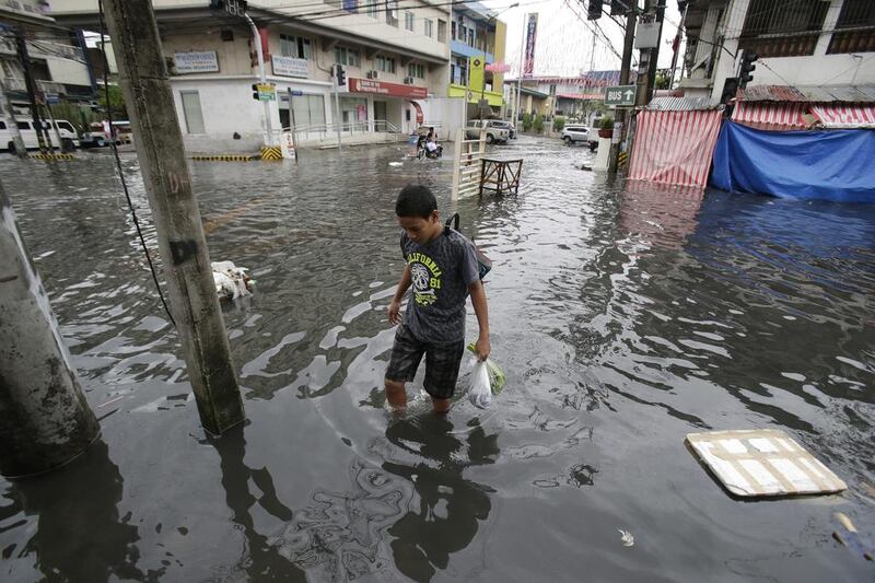 A man wades along a flooded street caused by rains from Typhoon Nock-Ten in Quezon city, north of Manila. Aaron Favila / AP