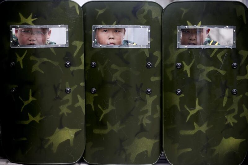 Young children peer through sight windows of protective shields during training at a summer boot camp on the outskirts of Beijing. Diego Azubel / EPA