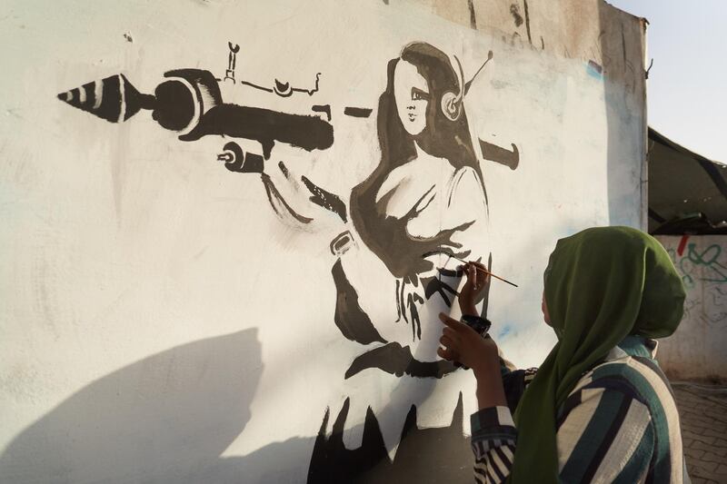 Safa Al Hadi paints satirical graffiti at the site. Getty