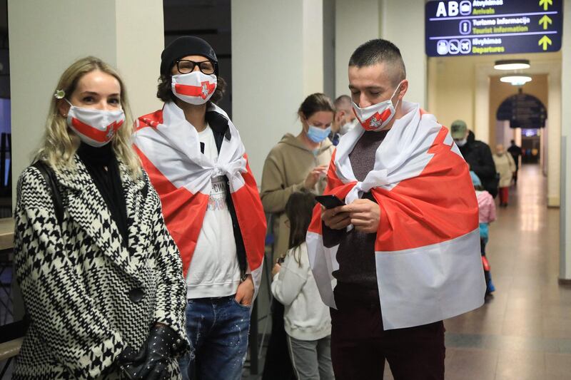 Young men and a woman wear the Belarus flag as passengers disembark from the Ryanair plane in Vilnius. AFP