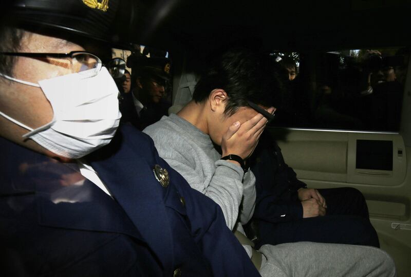 Suspect Takahiro Shiraishi (C) covers his face with his hands as he is transported to the prosecutor's office from a police station in Tokyo on November 1, 2017. 
The 27-year-old Japanese man, who was arrested after police found nine dismembered corpses rotting in his house, has confessed to killing all his victims over a two-month spree after contacting them via Twitter, media reports. / AFP PHOTO / JIJI PRESS / STR / Japan OUT