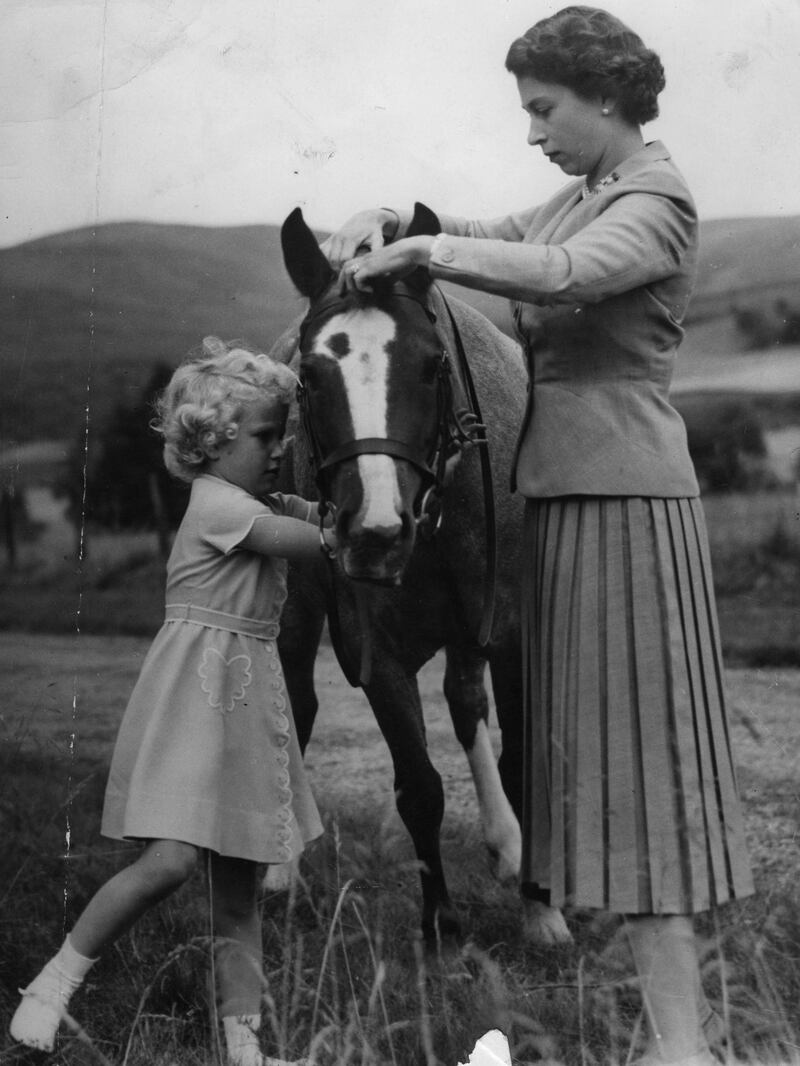 Princess Anne helps her mother, Queen Elizabeth II, fit the bridle to the pony Greensleeves, on the grounds of Balmoral Castle, during the royal family's summer holiday in Scotland in 1955. PA Images via Reuters