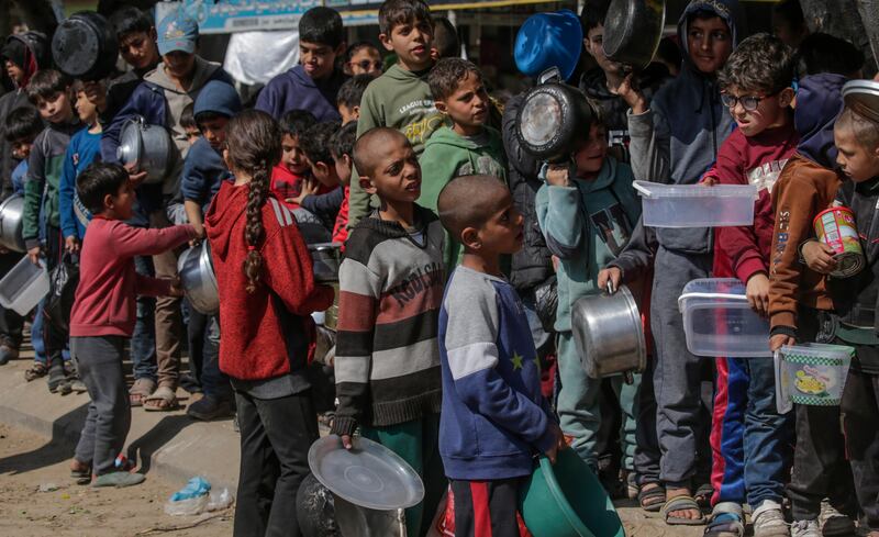 Internally displaced Palestinian children queue with pots and containers waiting to receive food provided by Arab and Palestinian donors in Deir Al Balah city in the central Gaza Strip. EPA