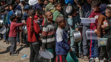 Internally displaced Palestinian children queue with pots and containers waiting to receive food provided by Arab and Palestinian donors in Deir Al Balah city in the central Gaza Strip. EPA