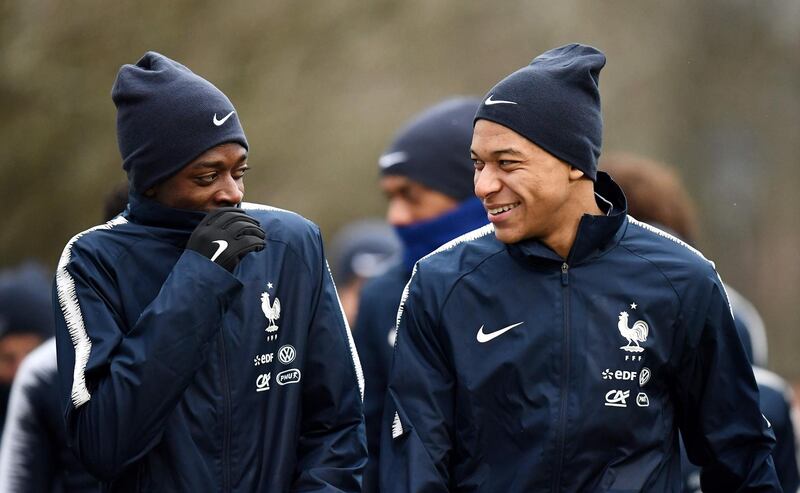 France's forward Ousmane Dembele (L) jokes with forward Kylian Mbappe before a training session in Clairefontaine-en-Yvelines, southwest of Paris, on March 19, 2018, as part of the team's preparation for the friendly football matches against Colombia and Russia.   / AFP PHOTO / FRANCK FIFE
