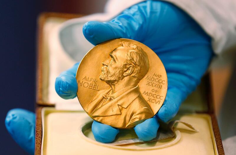 FILE - In this April 17, 2015, file photo, a national library employee shows a gold Nobel Prize medal in Bogota, Colombia. The Nobels, with new winners announced starting Monday, Oct. 5, 2020, often concentrate on unheralded, methodical, basic science. (AP Photo/Fernando Vergara, File)