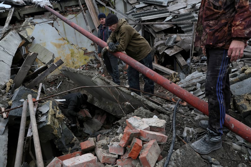 Workers dig out a tire from the rubble of a destroyed storage building at a grain processing center so they can use it for repairs in Siversk, Donetsk region. Reuters