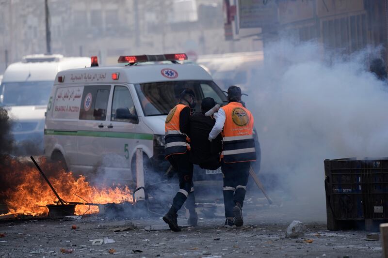 Medics carry a wounded Palestinian to receive treatment. AP