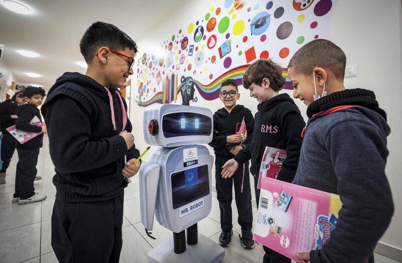 Palestinian students interact with a locally-made educational robot during a science class at a private school in Gaza City on November 30, 2021.  (Photo by MAHMUD HAMS  /  AFP)