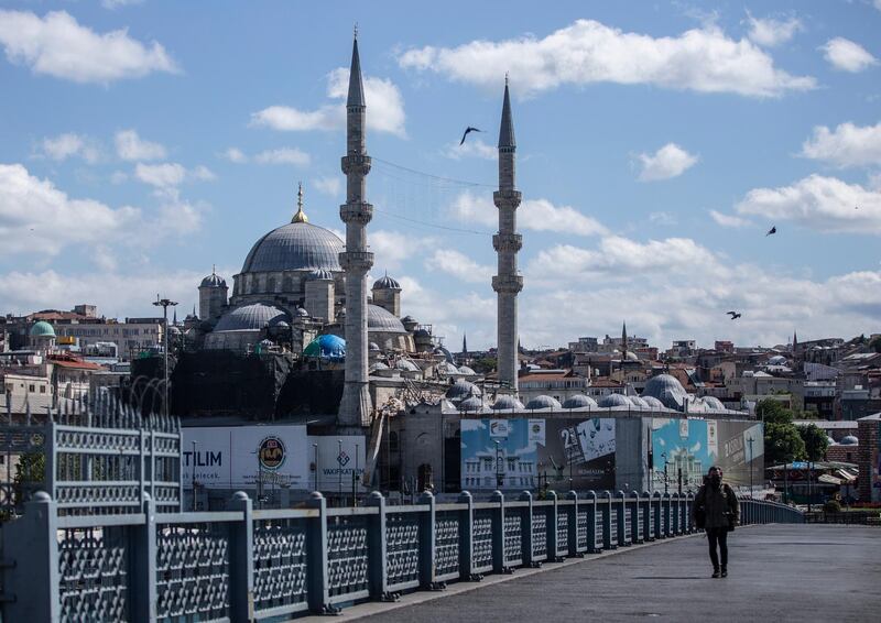 epa08439976 A journalist wearing a protective face mask walks on the Galata bridge on the Bosphorus backdropped by New mosque during a curfew amid the ongoing pandemic of the COVID-19 disease caused by the SARS-CoV-2 coronavirus in Istanbul, Turkey, 23 May 2020. President Erdogan announced a curfew in 81 Turkish cities, including Istanbul, from 23 to 26 May 2020 to curb the spread of the coronavirus disease (COVID-19) pandemic. The lockdown coincides with the festival of Eid al-Fitr, which marks the end of the Muslim fasting month of Ramadan.  EPA/ERDEM SAHIN