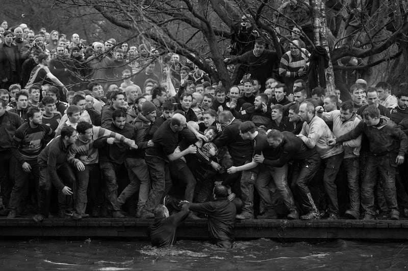 Oliver Scarff won 1st prize of the 'Sports - Singles' category for this image which shows members of opposing teams, the Up'ards and Down'ards, grapple for the ball during the historic, annual Royal Shrovetide Football Match in Ashbourne, Derbyshire. EPA/OLIVER SCARFF/AFP